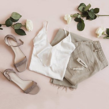 Bej arka planda kot pantolon, sandalet ve çiçek demeti. Kadın günlük bahar kıyafetlerinin en üst görüntüsü. Moda tarzı kadın kıyafetleri. Düz yatıyordu