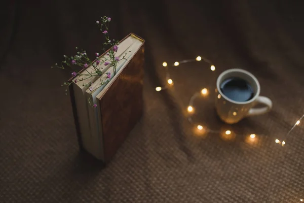 Um livro com flores e xícara de café no fundo escuro vista superior — Fotografia de Stock