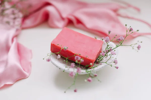 Spa composition with pink soap bar with ceramic soap dish, silk babric and flowers — Stock Photo, Image
