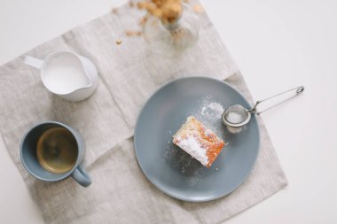 Sabah kahvaltısı bir parça ev yapımı kek, sürahi ve bir fincan kahveyle masada.