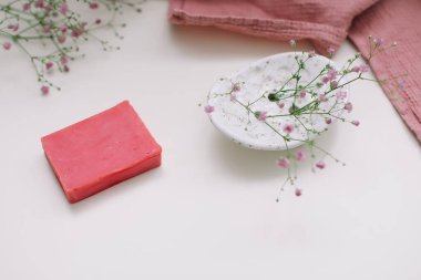 Beyaz çiçekli arka planda el yapımı doğal sabun. Sabun yapımı. Sabun kalıpları. Spa, cilt bakımı. Yukarıdan beyaz masadaki doğal organik spa ürünleri. 