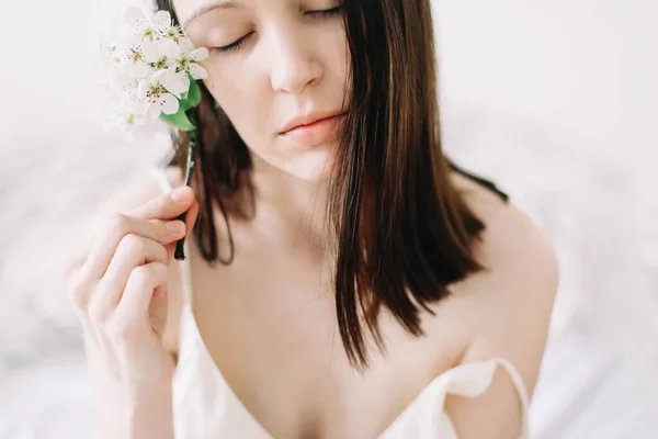 Mujer hermosa joven con flores sobre fondo blanco. Tierno retrato puro. Cuidado de la piel y salud de la cara, maquillaje natural . — Foto de Stock