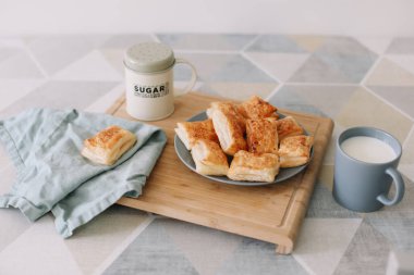 Kahvaltıda poğaça ve bir bardak süt. Mutfak masasında yeni pişmiş ev yapımı hamur işi.. 