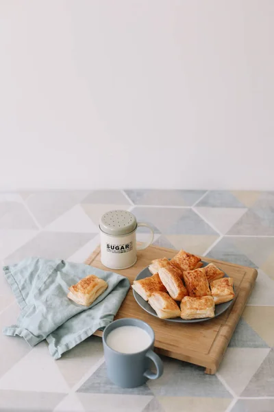 Sarapan dengan roti puff dan segelas susu. pastri buatan sendiri yang baru dipanggang di meja dapur. — Stok Foto