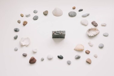 Spa background with sea shells and pebbles and a organic soap bar on white. Flat lay, top view, minimal spa concept