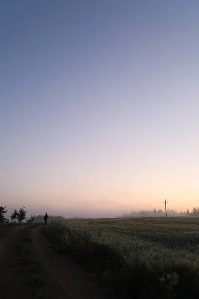 Silhouette eines Mannes, der bei Sonnenaufgang in einer malerischen Landschaft wandelt — Stockfoto