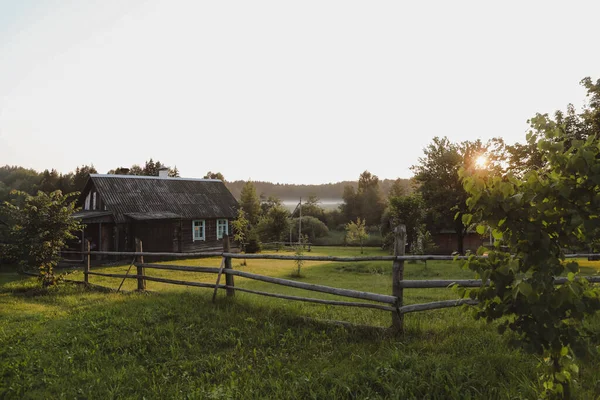 Trä europeiskt hus i en pittoresk landsbygd vid solnedgången på sommaren — Stockfoto