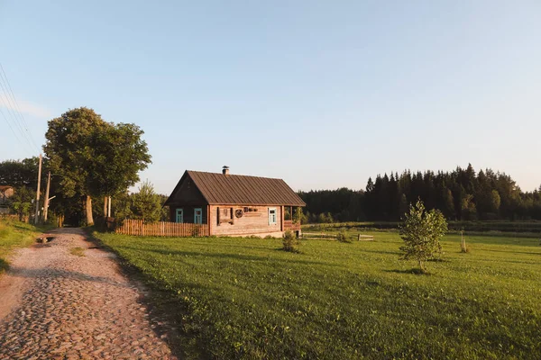 Dřevěný evropský dům v malebné krajině při západu slunce v létě — Stock fotografie