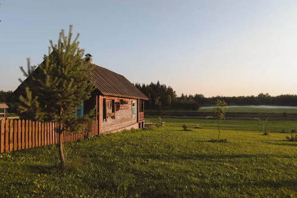 Dřevěný evropský dům v malebné krajině při západu slunce v létě — Stock fotografie