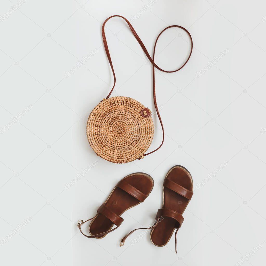  Top view of stylish female sandals and a wicker rattan bag isolated on white