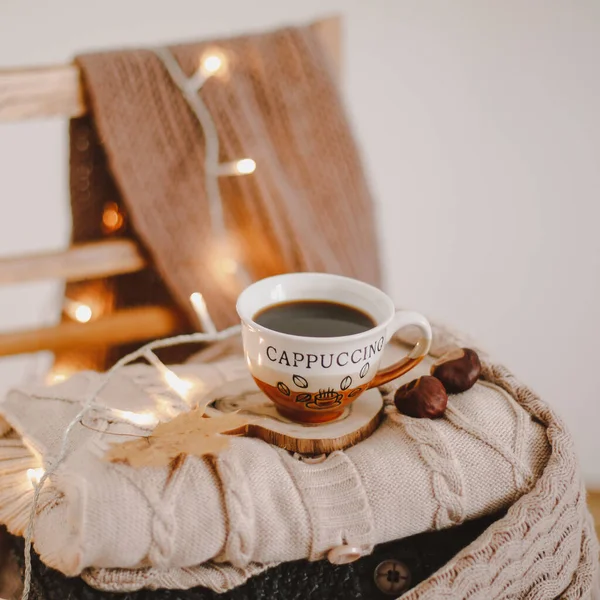 Una taza de café en una tela a cuadros beige de punto con luces bokeh — Foto de Stock