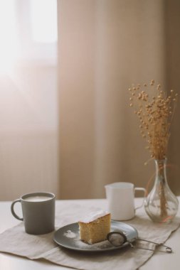 Sabah kahvaltısı bir parça ev yapımı kek ve masa örtülü bir fincan kapuçino.. 