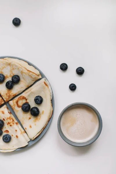 Sarapan dengan secangkir cappuccino dan pancake dengan blueberry di atas tampilan latar belakang putih — Stok Foto