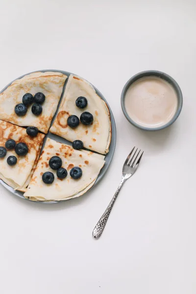 Sarapan dengan secangkir cappuccino dan pancake dengan blueberry di atas tampilan latar belakang putih — Stok Foto