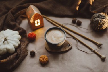 Sonbahar, evin iç kısımlarında bir fincan, mumlar ve ekoseyle sakin bir hayat sunar. Hygge ev dekoru. Cadılar Bayramı ve Şükran Günü konsepti 