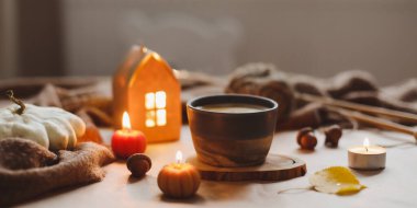 Sonbahar sıcacık ev içleri, bir fincan, mumlar, ekose kumaşlar. Hygge ev dekoru. Cadılar Bayramı ve Şükran Günü konsepti 