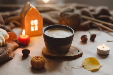 Sonbahar sıcacık ev içleri, bir fincan, mumlar, ekose kumaşlar. Hygge ev dekoru. Cadılar Bayramı ve Şükran Günü konsepti 