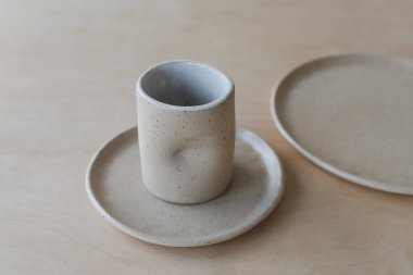 Ahşap masa manzaralı seramik bardak ve tabaklar. Minimalist el yapımı seramik sofra takımı ve çömlek