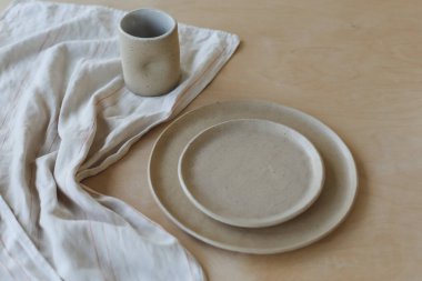 Ahşap masa manzaralı seramik bardak ve tabaklar. Minimalist el yapımı seramik sofra takımı ve çömlek