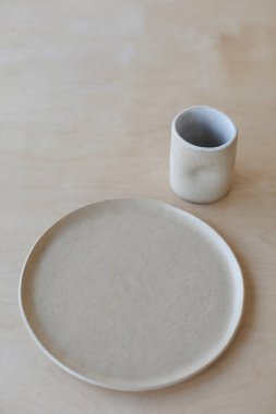 Ahşap masa manzaralı seramik bardak ve tabaklar. Minimalist el yapımı seramik sofra takımı ve çömlek