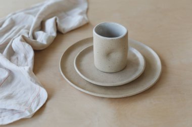 Ahşap masa manzaralı seramik bardak ve tabaklar. Minimalist el yapımı seramik sofra takımı ve çömlek