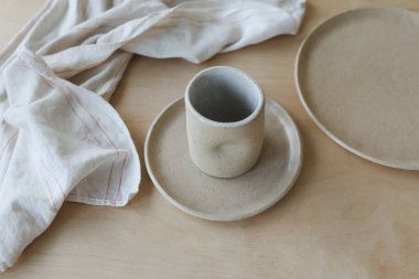 Ahşap masa manzaralı seramik bardak ve tabaklar. Minimalist el yapımı seramik sofra takımı ve çömlek