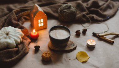 Sonbahar, evin iç kısımlarında bir fincan, mumlar ve ekoseyle sakin bir hayat sunar. Hygge, Cadılar Bayramı ve Şükran Günü konsepti 