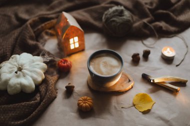 Sonbahar, evin iç kısımlarında bir fincan, mumlar ve ekoseyle sakin bir hayat sunar. Hygge, Cadılar Bayramı ve Şükran Günü konsepti 