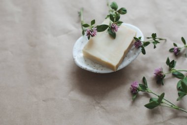 El yapımı organik spa sabunu. Çiçekler seramik sabun çanağında. El yapımı kağıt zemin üzerinde.