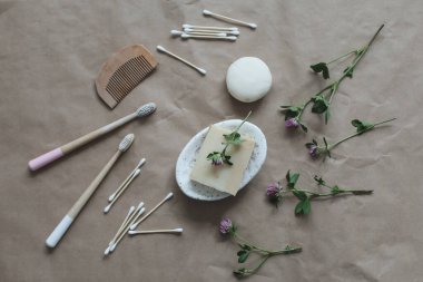 Çevre dostu ürünler. El yapımı doğal sabun, ahşap diş fırçası, pamuk çubuğu ve el işi kağıt arka plan görünümlü saç fırçası.