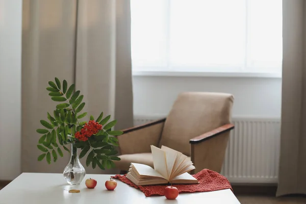 Herfst stilleven met een rowan tak in een vaas, boek en appels in een gezellig interieur — Stockfoto