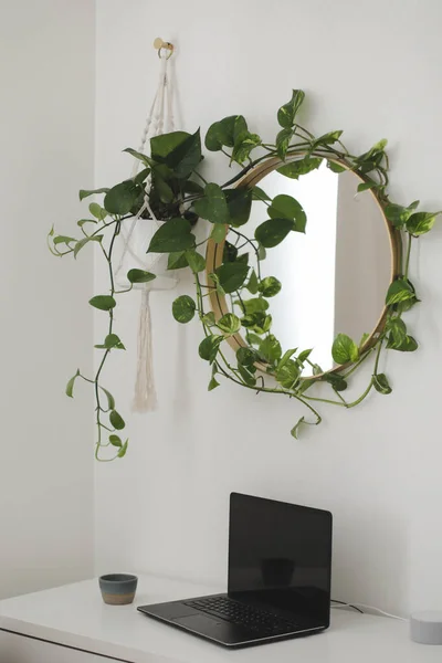 Stijlvolle werkplek thuis met een laptop op tafel en een ronde spiegel met daarboven een plant — Stockfoto