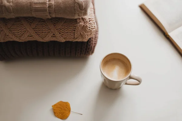 Aconchegante confortável inverno e outono em casa atmosfera e ainda a vida com uma xícara, livro e blusas quentes — Fotografia de Stock