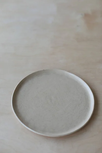 Piatto in ceramica su un tavolo in legno vista dall'alto. stoviglie e ceramiche minimaliste fatte a mano — Foto Stock