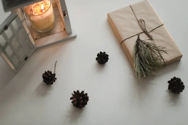 Flatlay d'hiver avec un cadeau de Noël et de nouvel an en papier artisanal, bougie, perruque de pin et cônes vue de dessus — Photo