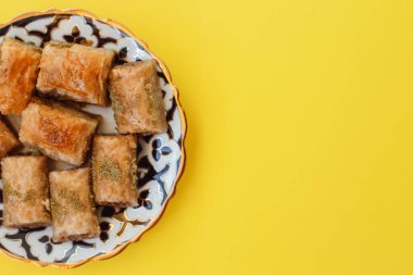 walnut, pistachio turkish style antep baklava presentation and service. top view of baklava with pistachio on a yellow background