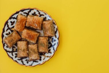 walnut, pistachio turkish style antep baklava presentation and service. top view of baklava with pistachio on a yellow background