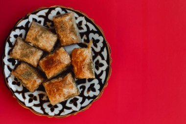 Turkish Ramadan Dessert Baklava isolated on red background. Traditional arabic dessert baklava with cashew, walnuts and cardamom