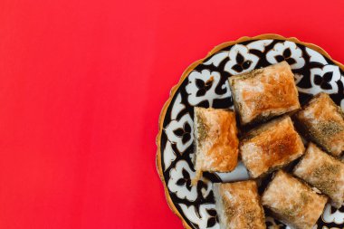 Turkish Ramadan Dessert Baklava isolated on red background. Traditional arabic dessert baklava with cashew, walnuts and cardamom