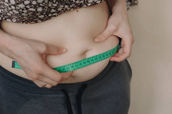 Fat woman measure tape your fat belly on a light background