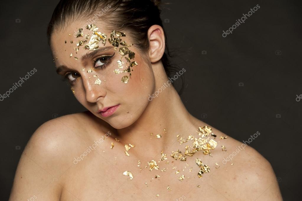 Magnifique portrait de femme brune avec paillettes d\u0027or sur son visage et ses cheveux en chignon sur un fond noir \u2014 Image de eugenef