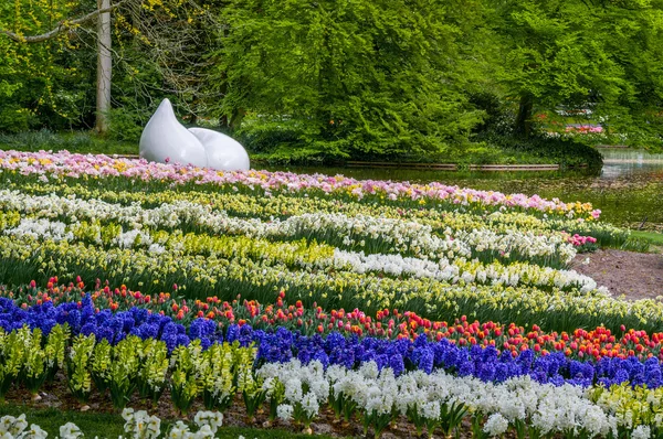 Monumento a la gota con narcisos coloridos y tulipanes, Parque Keukenhof, Lisse en Holanda —  Fotos de Stock