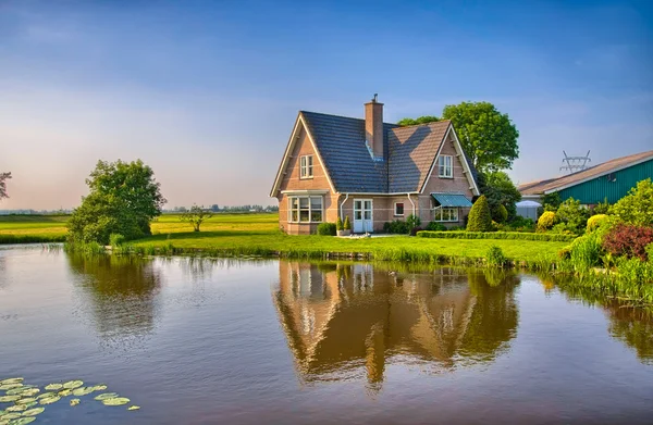 Red bricks house in countryside near the lake with mirror reflec