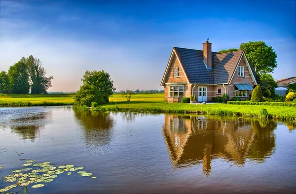 Casa de tijolos vermelhos no campo perto do lago com espelho reflec — Fotografia de Stock