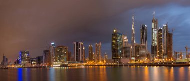 DUBAI, BAE - 24 Mart 2017: Fırtınalı bulutlarla dolu yeni kanal ve şehir merkezi üzerindeki köprüyle birlikte akşam silueti.