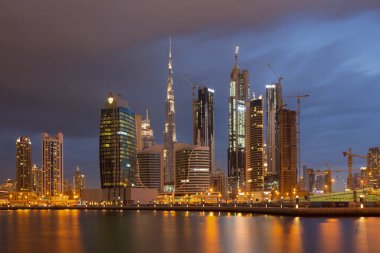 DUBAI, BAE - 24 Mart 2017: Fırtınalı bulutlarla dolu yeni kanal ve şehir merkezi üzerindeki köprüyle birlikte akşam silueti.