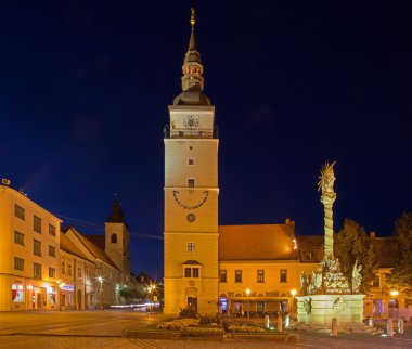 Trnava, Slovakya - 14 Ekim 2014: Main çan kulesi ve alacakaranlıkta kutsal Trinity Barok sütun ile kare.