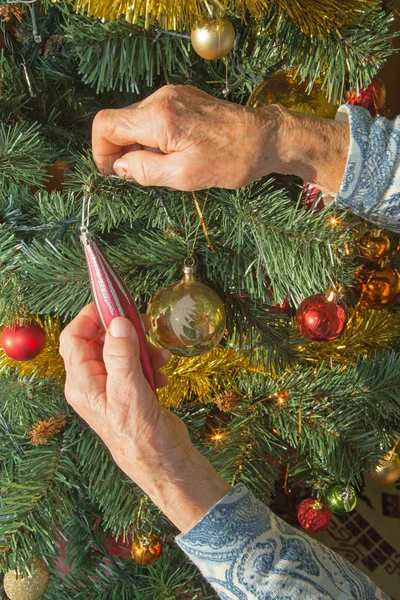 Hands of old woman and christmas decoration — Stock Photo, Image