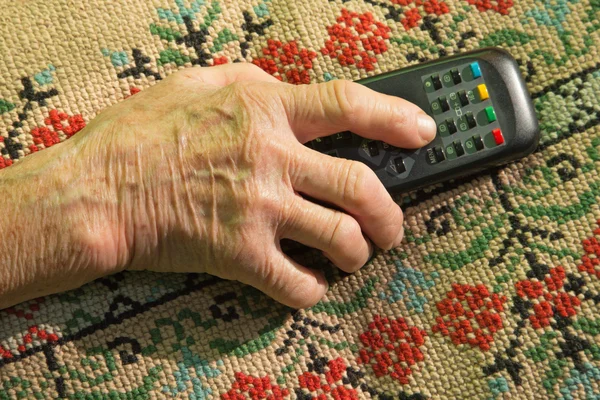 Hand van oude vrouw met Tv stuurprogramma — Stockfoto