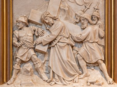 VIENNA, AUSTRIA - DECEMBER 17, 2014: Simon of Cyrene help Jesus to carry his cross. Relief as one part of Cross way cycle in Sacre Coeur church by R. Haas from end of 19. cent. clipart